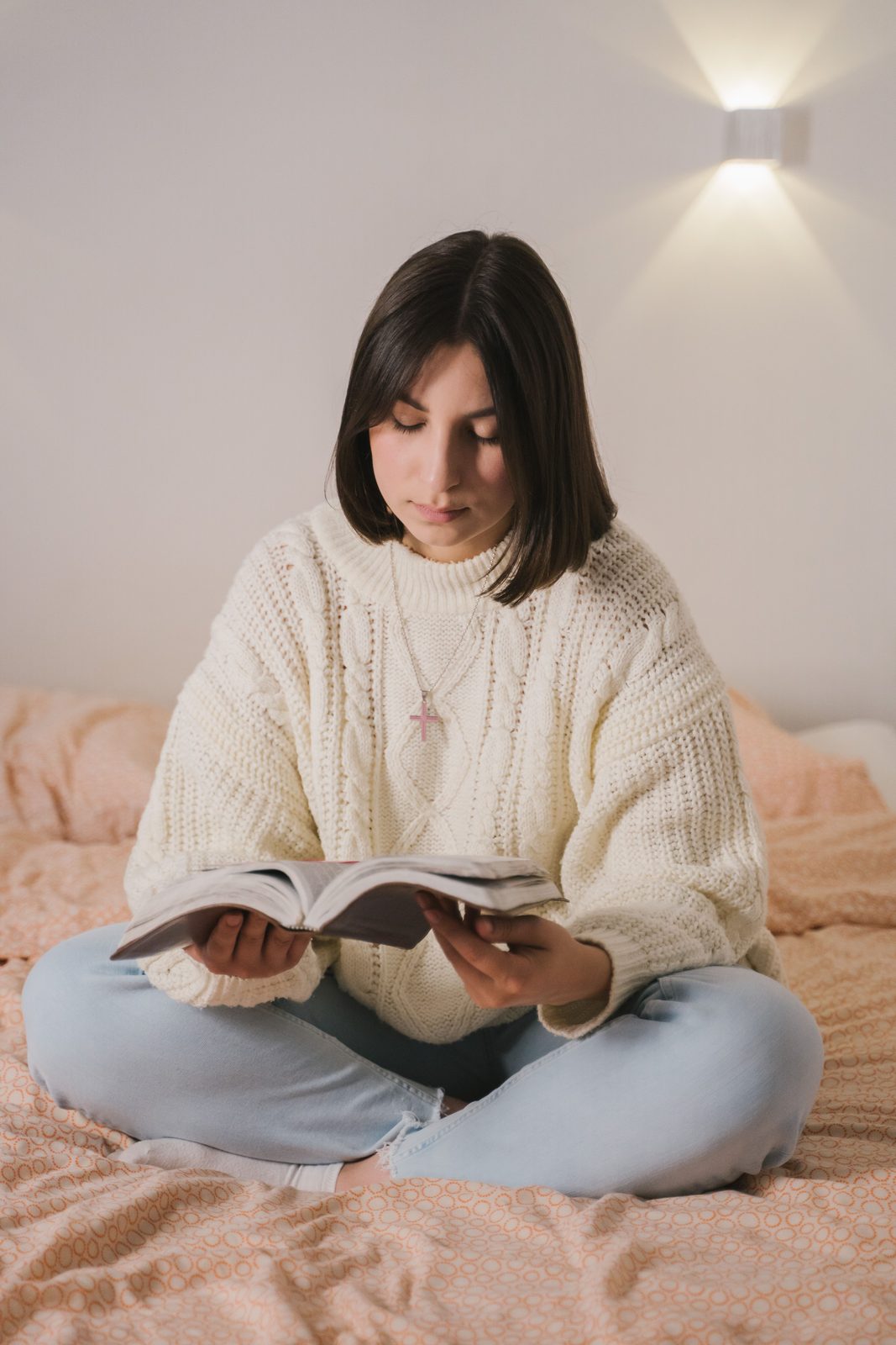 Joven leyendo la Biblia en su cama con la luz de la mañana